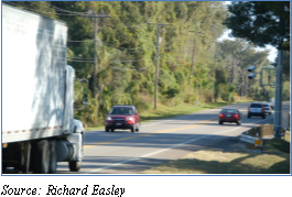 Traffic, including a truck, on a highway near a camera mounted on a roadside pole for an electronic screening system. Source: Richard Easley.