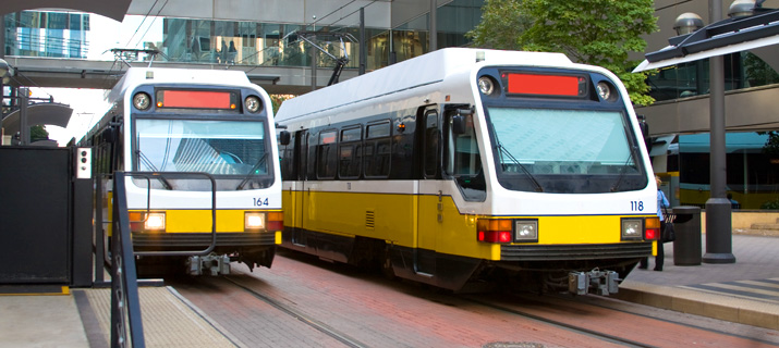 Two light-rail trains at station in urban area.