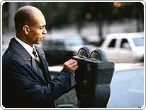 man inserts coins in a parking meter