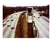 Photograph of traffic surveillance camera positioned between eight lanes of traffic