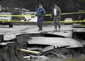 Photograph of two workers surveying earthquake damage to roadway