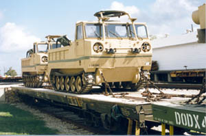photo of two military transport vehicles on a heavy duty flatbed rail car