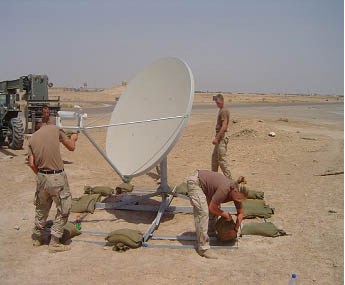photo of a three soldiers setting up a mobile satellite dish in the field