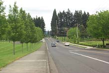 photograph of a typical roadway in the City of Tualatin. The picture shows a three-lane roadway with two-way left-turn lanes, a sidewalk, and landscape.
