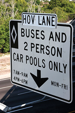 Photo. A highway sign reading “HOV Lane. Buses and 2 person car pools only, 7 AM - 9 AM, 4 PM – 6 PM, Mon - Fri.”