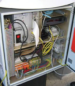 Photo. Close up view of centralized processing equipment showing multicolored cables and wires, and various machines.