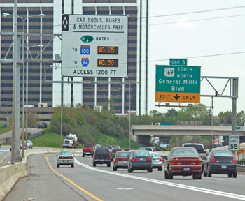 Photo. A dynamic message sign above a highway in Minnesota, listing dynamic pricing  for high-occupancy tolls (HOT) lanes. The rate to Route 100 is shown at $0.25 and the rate to Route 94 is shown at $0.50. Car pools, buses, and motorcycles are free.