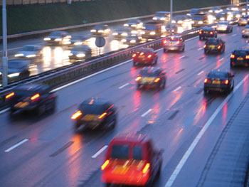 Photo. Cars driving during rush hour on a highway, with heavier traffic travelling in one direction.