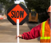 A person holding a “Slow” sign paddle in a work zone.