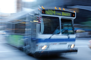 Photo. A blurred close-up view of a bus driving down the street.