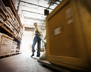 Photo shows a man pulling a loaded hand truck in a warehouse environment.