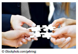 Photo of four people holding pieces of a puzzle. Copyright iStockphoto.com/gehringj