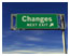 Photograph. A green roadway sign stating “Changes Next Exit” represents “culture of historical practices/resistance to change.”