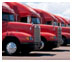 Photograph. The cabs of several large tractor-trailers lined up in a row represent “lanes that are not full width create safety issues for large trucks.”