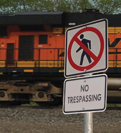 Figure 2.1 is a photograph showing a sign that forbids trespassing at a freight rail yard.