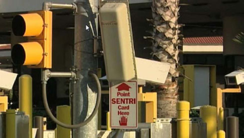 Figure 4. Photograph showing RFID card reader used in the SENTRI program (4). This photograph shows a radio-frequency identification card reader attached to a pole that also has a signal light. A sign below the reader says “Point SENTRI Card Here.”