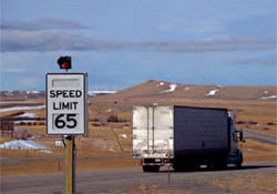 Photo. Example of Wyoming DOT’s use of variable speed limits.  The current speed limit for a stretch of highway is displayed on a speed limit sign with a red light mounted on the top.