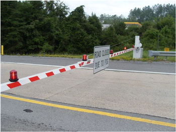 Photo of a swing gate blocking a road. On the gate is a static sign that reads, Road closed due to fog.