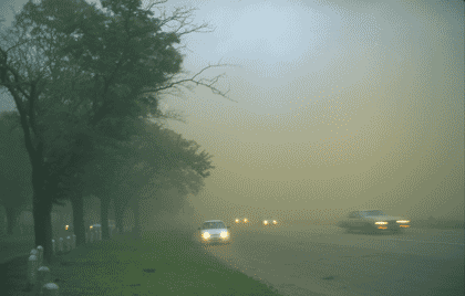 Picture of traffic on a roadway in thick fog.
