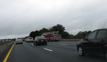 Picture of traffic moving along a roadway with a fire truck in view.