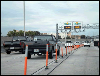 A photograph showing orange pylons in a raised curb separation on interstate.