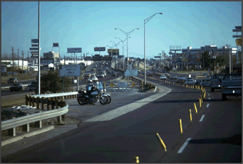 A photograph of enforcement officers monitoring traffic and identifying unauthorized vehicles where two motorcycle officers sit in the shoulder lane watching vehicles enter the managed lane.