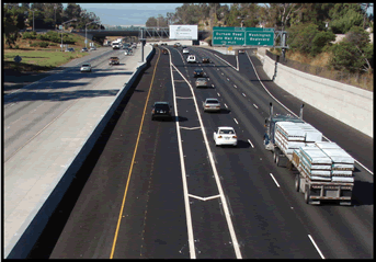 A photograph of an interstate section showing striping of slip ramp access in the left lanes.