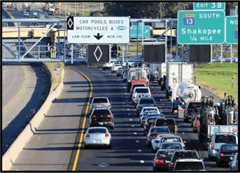 A photograph of an interstate where the left lane has an overhead sign indicating an HOV lane.