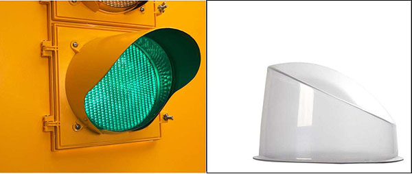 Figure 4. Fortran Snow Sentry Lens Cover. This image has two photographs. On the left, there is a close-up of a green traffic light, which is lit. There is an extended visor over the top of the green light. To the right, there is a photograph of a white lens cover, which is laying flat, with a domed top and a longer edge on its left side and a shorter edge on the right side.
