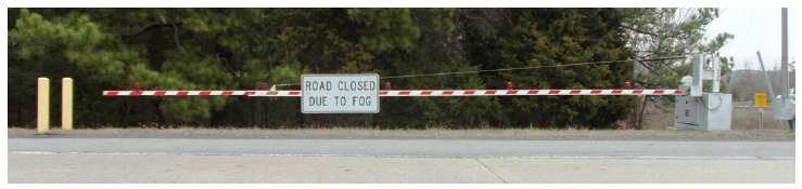 A mastarm used to close the roadway containing a sign that reads 'Road Closed Due to Fog'.