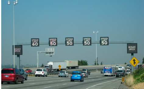 ATM lane control signage, with one sign per lane, is mounted on gantry over a multi-lane highway.