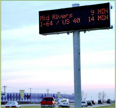 Large post-mounted permanent message sign displaying messages travel time messages to local traffic.