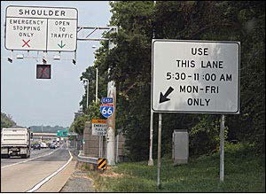 Picture of shoulder lane, including fixed signage indicating that the shoulder lane may be used at specific times and days of the week, and a dynamic lane control sign over the shoulder for displaying a red X or green arrow.