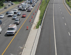 Photo of permanent physical barrier separating the managed and general purpose roadways. The barrier shown consists of guardrails, cement structures, and a grassy area.