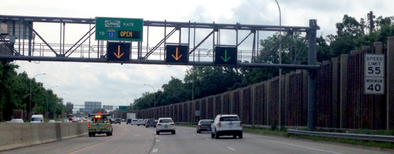 Photo of a highway where signage over the left-hand managed lane is indicating that the managed lane is open to all traffic.