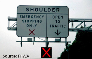 Photo of a road sign indicating either the shoulder is open to vehicle travel or only open for emergency stopping. An electronic light below the sign designates the current shoulder use status, in this case a red 'X' indicates the shoulder is closed to travel.