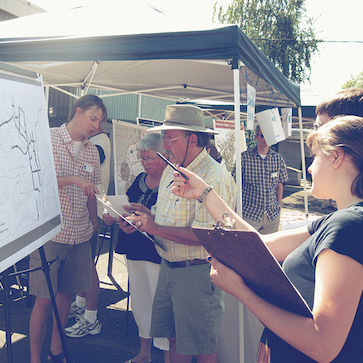 [photo 1]. This photo shows a public outreach event with two attendees and a presenter at a poster.