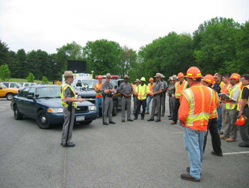 A photo of NYSDOT TIM Team assembled outside, showing a law enforcement officer while presenting to attending members of different emergency, safety and transportation agencies.