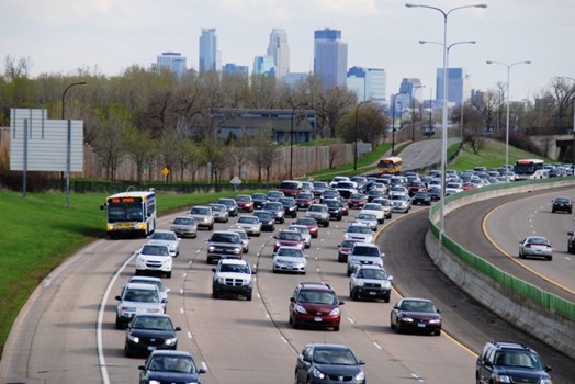 Photo of BOS operations in Minneapolis-St. Paul with a local transit bus operating on the right shoulder and mainline traffic using the four traditional travel lanes. The four travel lanes appear fairly congested, while the bus is traveling under free-flow conditions.