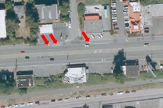 Aerial photo graph of SR 522 in Washington State with red arrows denoting the BOS pavement markings of interest. The first arrow points to white pavement markings reading “Transit Only” placed just downstream of an intersection. The second arrow, which is just upstream of the previous arrow denotes transverse white pavement markings on the shoulder (again, just downstream of the intersection). The third arrow denotes a white right-turn arrow pavement marking placed in the shoulder upstream of the intersection.