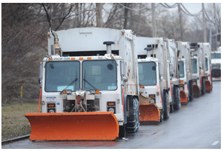 A line of snow plows wait for a weather event to begin.