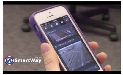 Figure 16 is a screen capture of the Tennessee Department of Transportation’s SmartWay traveler information service from a promotional video. It shows someone holding a smart phone on which the SmartWay service is open. The smart phone screen is showing two images of a roadway that allow the user to inspect traffic conditions.