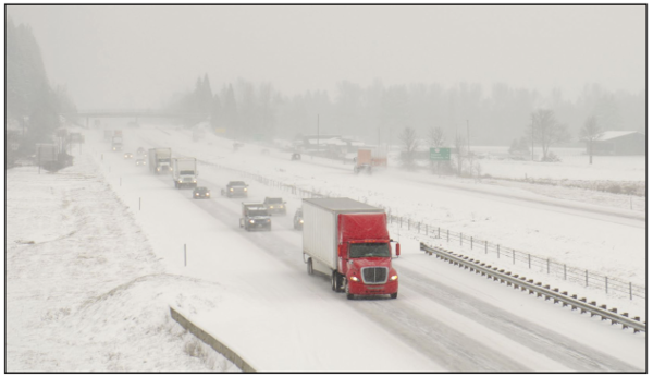 Images shows a restricted-access highway with long-haul trucks mixed with passenger traffic in snowy conditions.