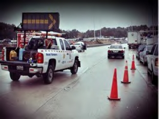 The image shows a lane blocked by traffic cones due to an accident and parallel lanes stuck filled with traffic.