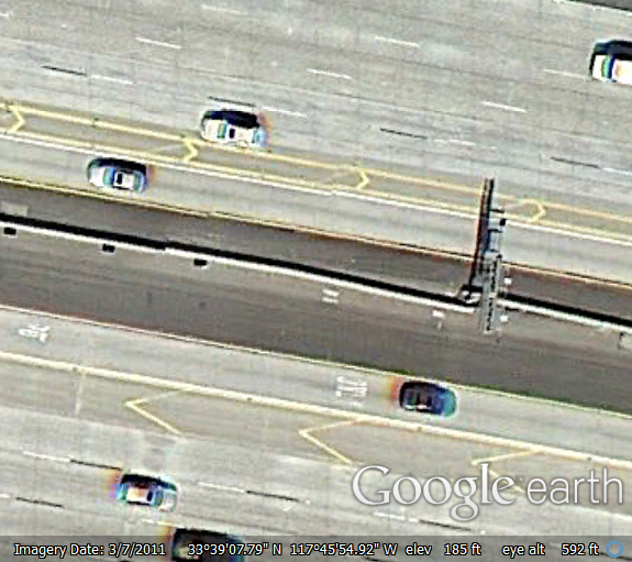 Figure 6. Graphic. Aerial photograph showing a portion of both sides of a freeway. The managed lanes on each side of the raised barrier are separated from the general-purpose lanes with a flush buffer that is wide. The wide buffer has chevrons marked within the buffer area.