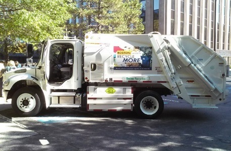 This is a picture ofthe side of a garbage truck with a solid panel under the main body of the truck, between the passenger cabin and the rear wheel.