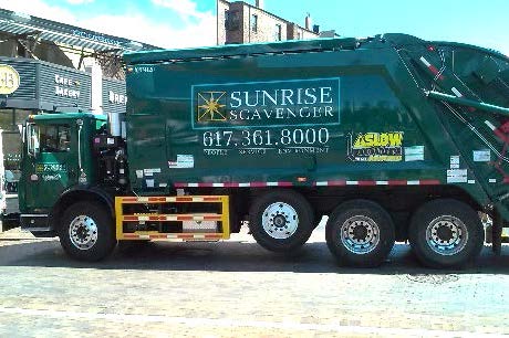 This is a picture of the side of a garbage truck with a guard consisting of three horizontal rails under the main body of the truck, between the passenger cabin and the rear wheel.