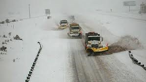 This picture shows cars and trucks in traffic on a highway with snow.
