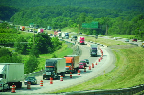 I–81 in Pennsylvania with congestion from construction.  Several orange and white construction barrels are depicted among a variety of freight trucks and cars.