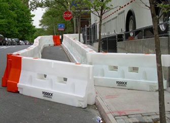 This photo shows longitudinal channelizing devices arranged to delineate a pedestrian walkway on the far right side of a street.
